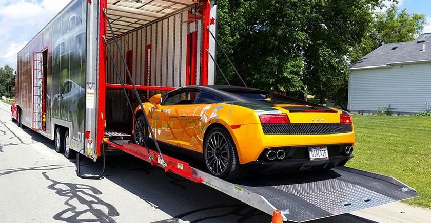 A yellow sport car being loaded onto a trailer for import.