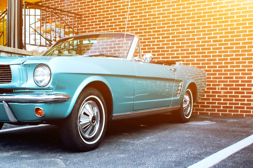 A vintage car parked in front of a brick building.