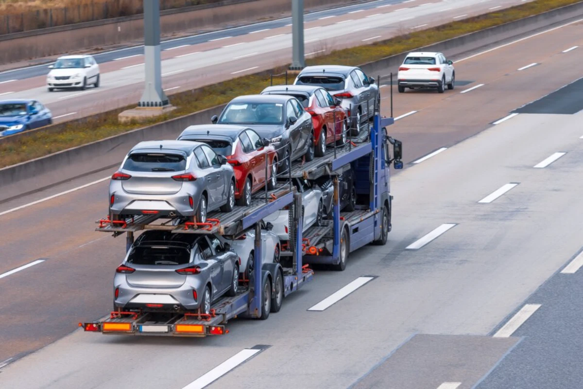 A truck transporting cars on a busy highway.