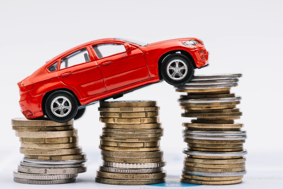 A red car perched on stacks of coins, symbolizing wealth and luxury.