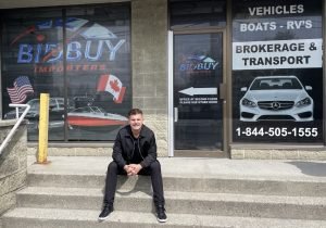 A man sitting on the steps of a business, in front of the Border123 shop