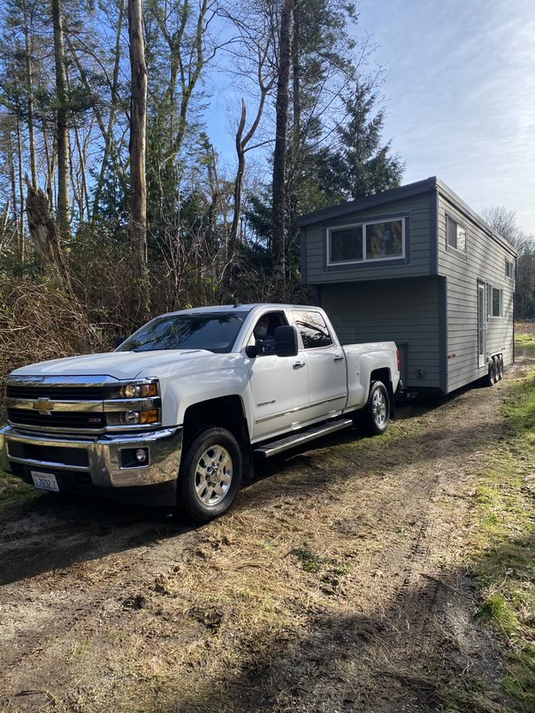 A white truck parked in front of a tiny house.