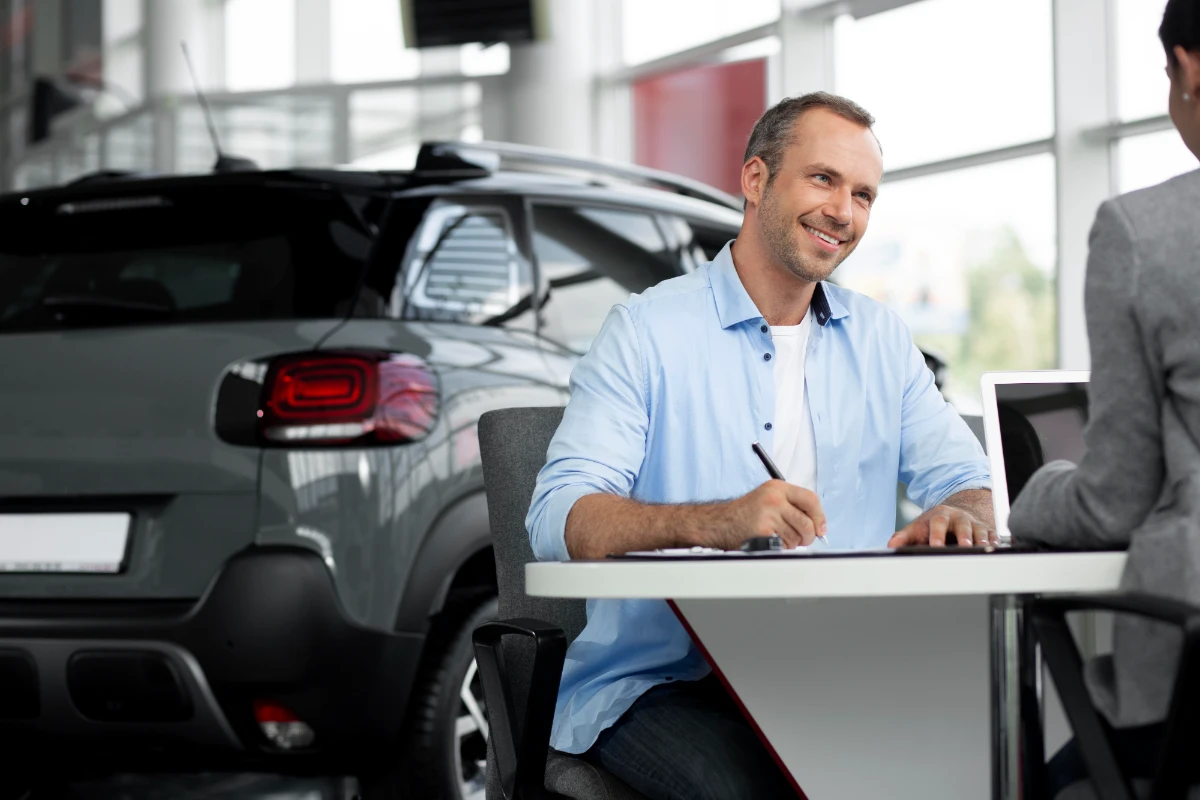 An image of a man and woman sitting at a table, with a car visible behind them