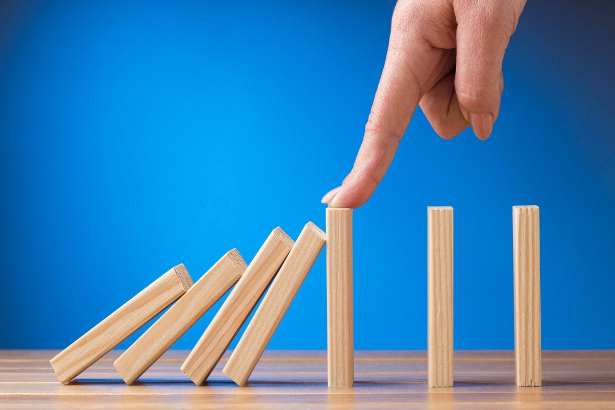 A person carefully stacks wooden blocks to create a domino tower.